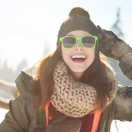 Mujer sonriente al aire libre en invierno, símbolo de energía y bienestar gracias a suplementos antioxidantes.