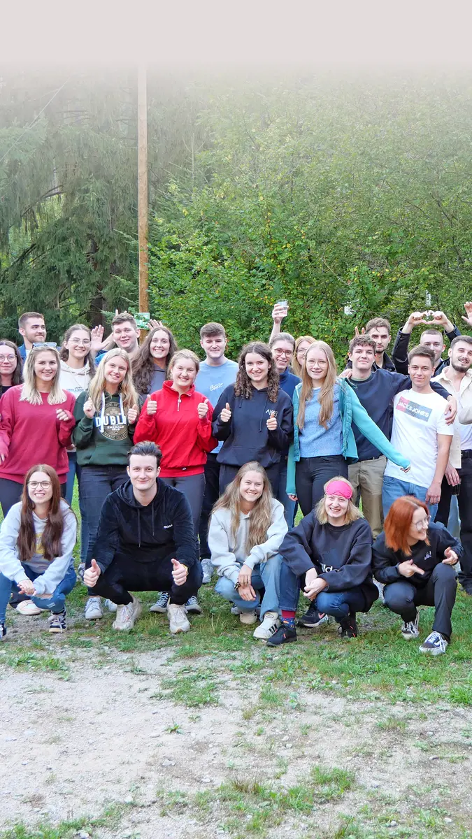 Gruppenbild: Heel-Azubis lachen in die Kamera und winken beim Azubi-Event.