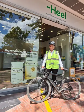 Heel Kolumbien Mitarbeiterin steht mit ihrem Fahrrad vor Heel-Apotheke.