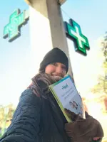 Heel Außendienstmitarbeiterin macht ein Selfie vor einer Apotheke.
