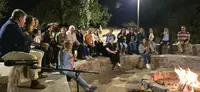 Heel Chile Mitarbeiter sitzen im Kreis um ein Lagerfeuer und feiern ausgelassen.