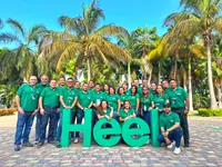 Heel Ecuador Mitarbeiter stehen als Gruppe vor großem Heel Logo vor Palmen.