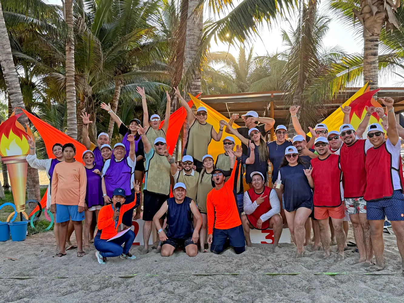 Heel Ecuador Mitarbeiter stehen als Gruppe am Strand und lachen in die Kamera. 