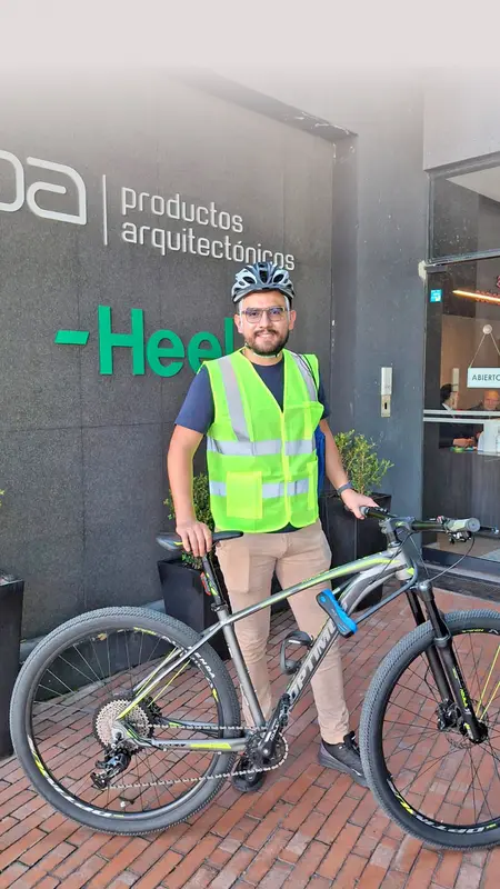 Heel Kolumbien Mitarbeiter steht mit Fahrrad vor Heel-Eingang.
