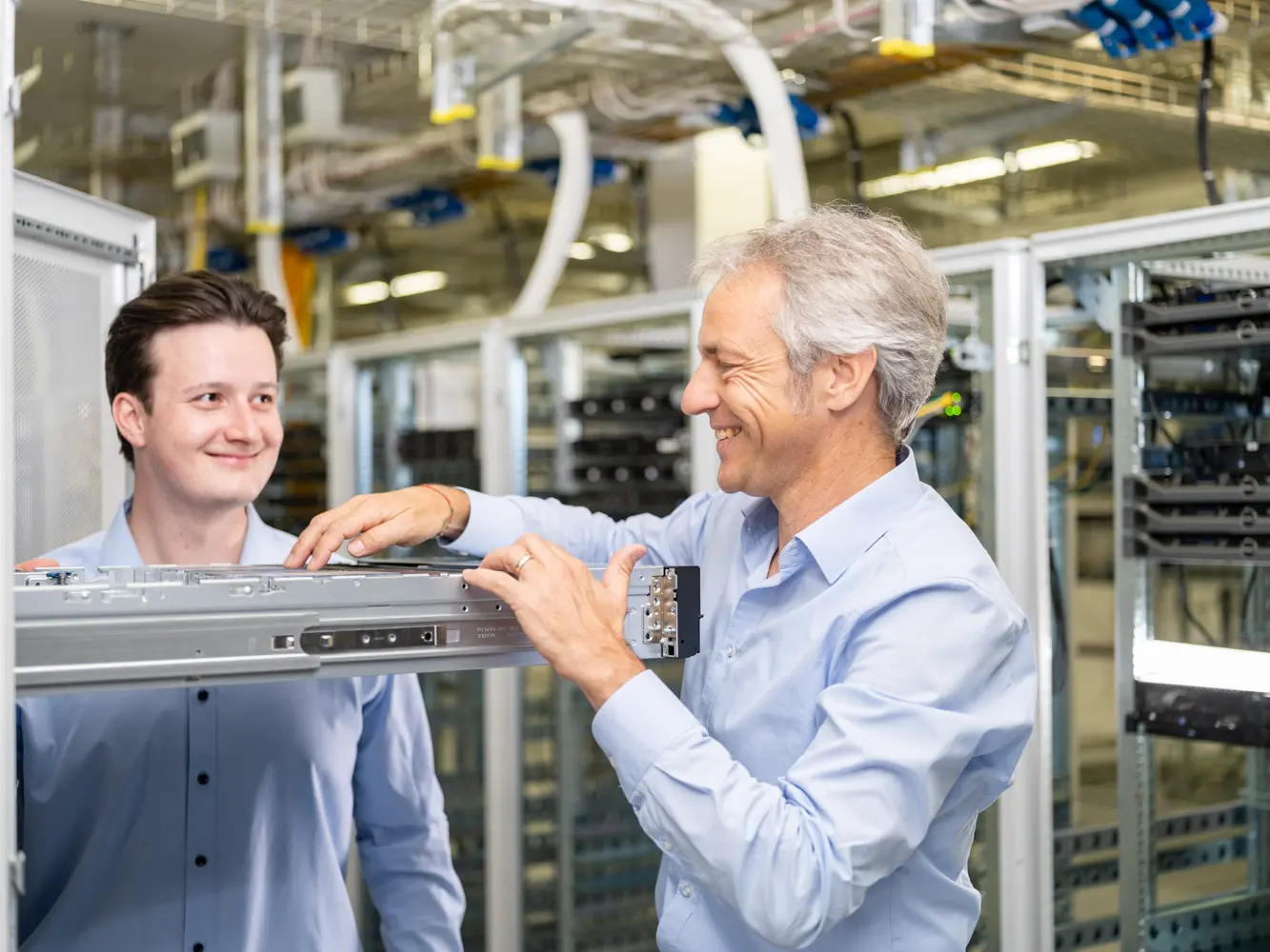 Zwei IT Mitarbeiter stehen in einem Serverraum und inspizieren einen Server-Rack.